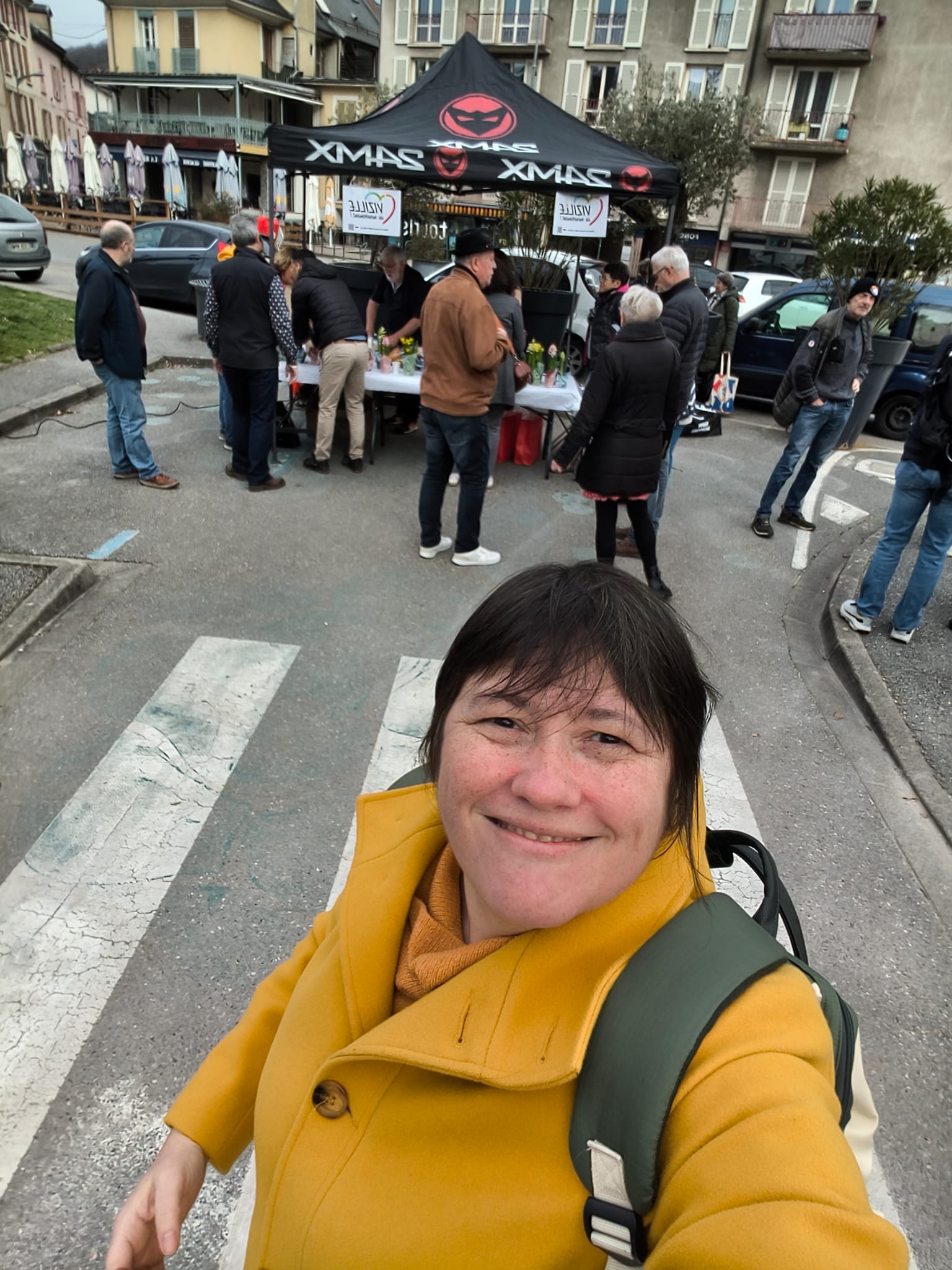 Selfie devant le stand — candidat souriant, stand VeM visible
