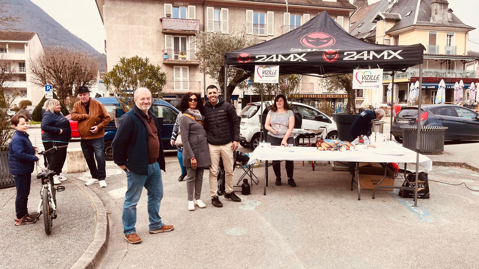 Groupe de candidats souriants devant le stand VeM, montagne en fond