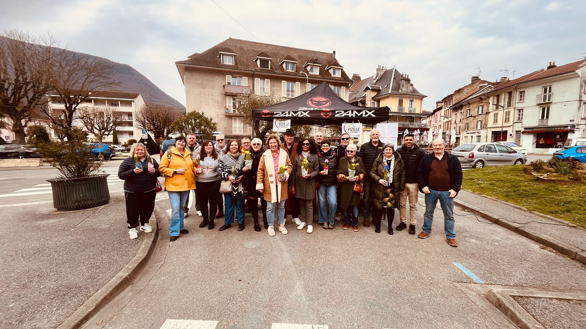 L'équipe VeM au complet devant le stand, chacun tient un bouquet de fleurs jaunes de printemps