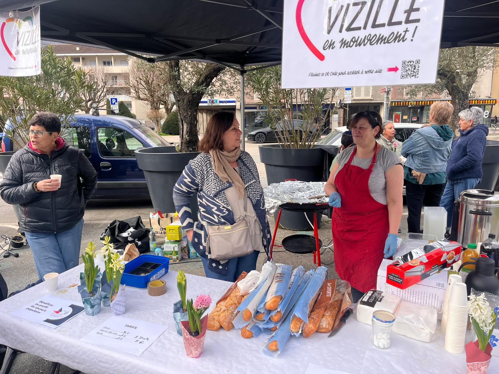 Stand VeM avec banderole, diots et fleurs, public autour